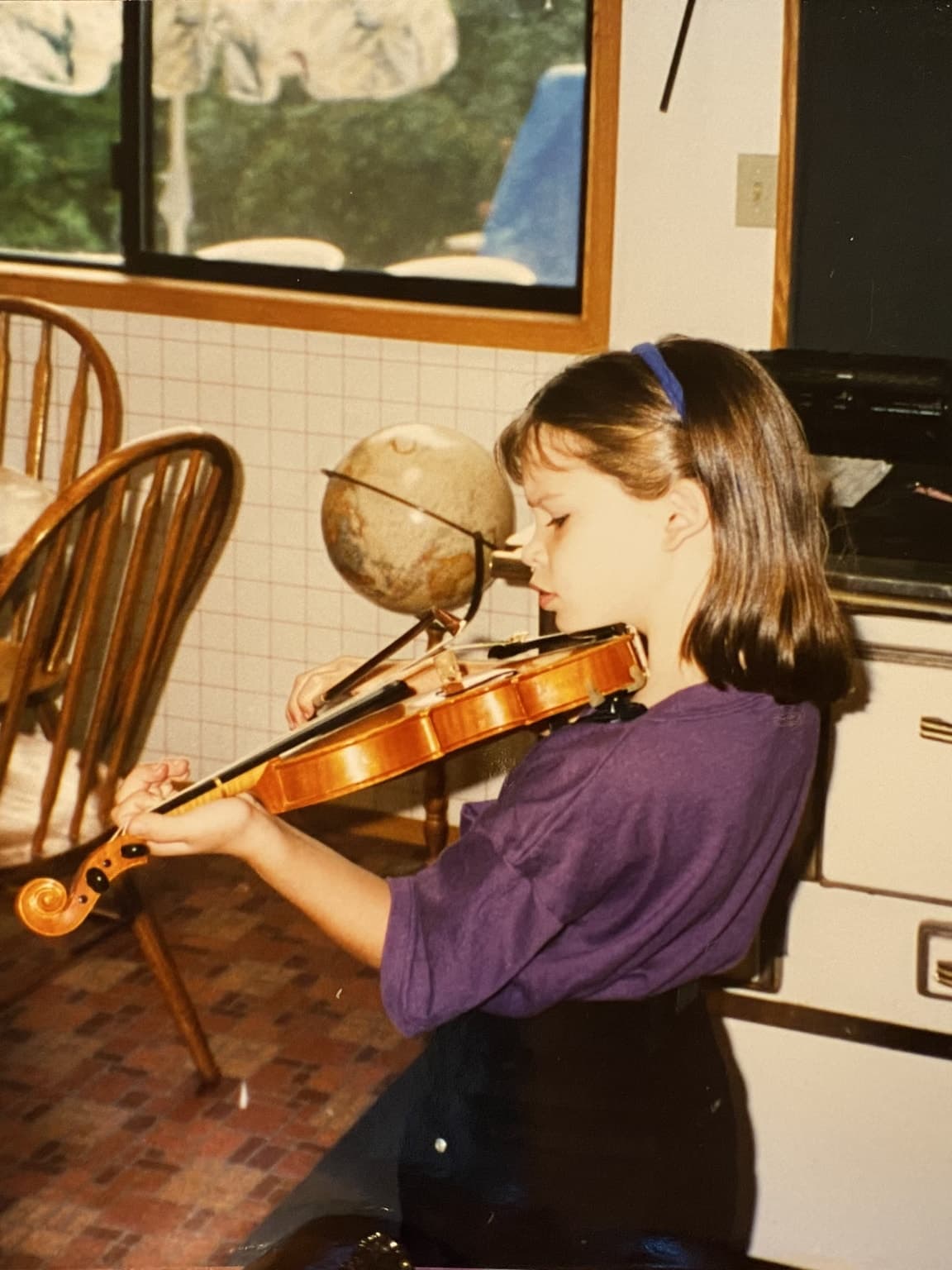 Liz as a child playing the violin at home.